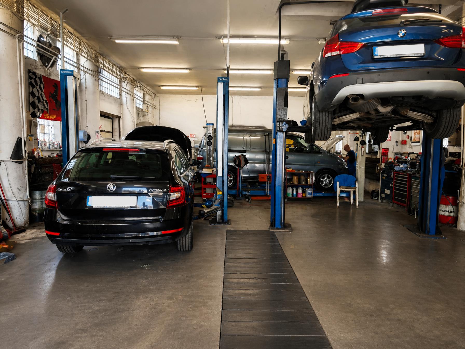 Interiér autoservisu s viacerými vozidlami na zdvihákoch.