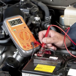 Auto mechanic checking car battery voltage